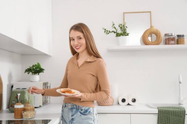 Mutfakta bir tabak tost ve fıstık ezmesi olan genç bir kadın.