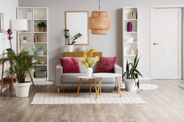 Oturma odasının içinde raflar, sehpalar ve kanepede mor yastıklar var.