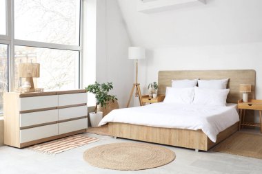 Beyaz battaniyeli rahat yatak ve şık yatak odasında yumuşak yastıklar.