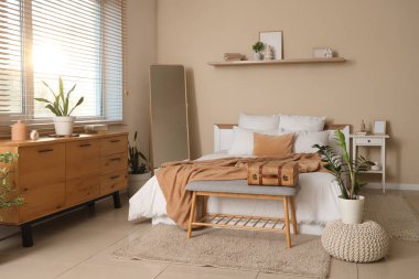 Büyük aynalı, yumuşak banklı ve raflı rahat bir yatak odası.