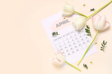 Nisan 'ın kağıt takvimi ve renk arkaplanındaki güzel bahar çiçekleriyle kompozisyon