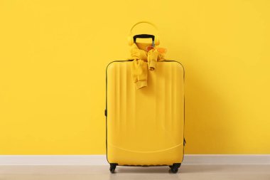 Odada sarı duvarın yanında kulaklıklı, gözlüklü ve kazaklı çanta.