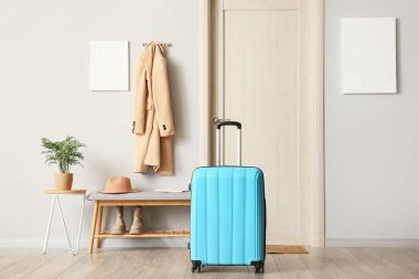 Koridorun sonundaki bankta ve mavi bavulla.