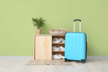 Bavul ve ayakkabı koridordaki yeşil duvarın yanında duruyor.