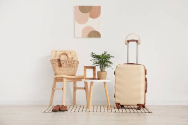 Masa, sandalye ve bavul beyaz duvarın yanında.