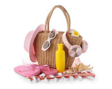 Beyaz arka planda izole edilmiş güneş kremi, kulaklık ve plaj aksesuarlarıyla dolu bir çöp torbası.