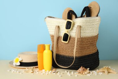 Hasır çanta, güneş kremi şişeleri, renkli arka planda taşlar ve plaj aksesuarları, yakın plan