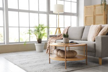 Oturma odasının içinde yumuşak kanepe, masa ve lamba var.