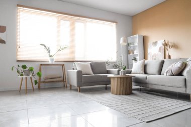 Gri koltukları, masası ve raf ünitesi olan oturma odasının içinde.