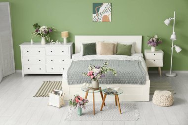 Yatak odasının içi, rahat yatak odası, masalar ve güzel çiçekler.