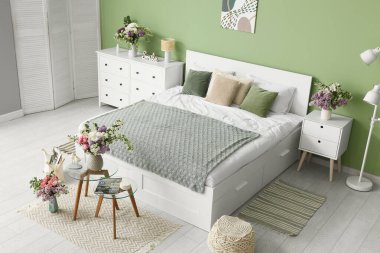 Yatak odasının içi, rahat yatak odası, masalar ve güzel çiçekler.