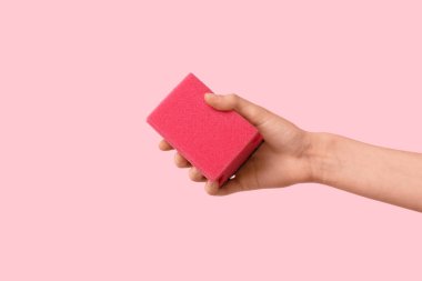 Pembe arka planda temizlik için el ele tutuşan sünger.