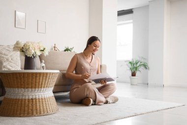 Evde dinlenirken dergi okuyan genç bir kadın.