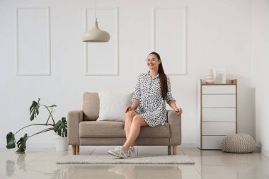 Evde kanepede oturan genç kadın