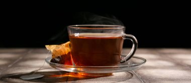 Bir fincan sıcak çay koyu arka planda, yakın plan.