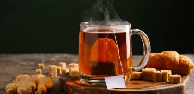 Zencefilli ve şekerli bir fincan sıcak çay koyu arka planda, yakın plan