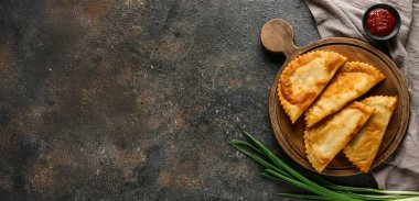 Lezzetli cheburekler, sos ve koyu grunge arka planda taze soğan.