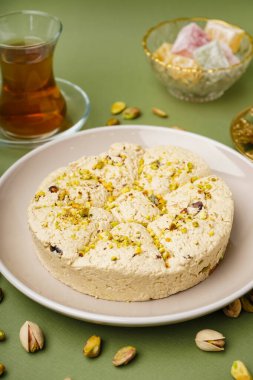 Yeşil arka planda fıstıklı Tahini Halva tabağı.