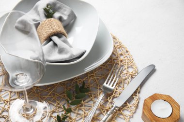 Süslü masa ayarı ve grunge beyaz arkaplan üzerinde mum ile hasır mat