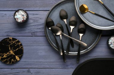 Temiz tabaklar, çatal bıçak takımı ve mavi ahşap masada bardak altlığı.