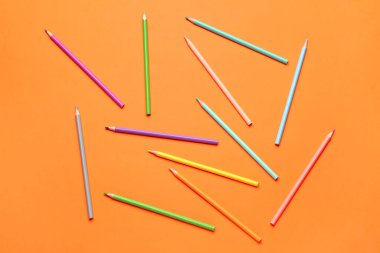 Turuncu arka planda renkli kalemler grubu