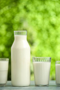 Mavi masada bardaklar ve bir şişe taze süt.