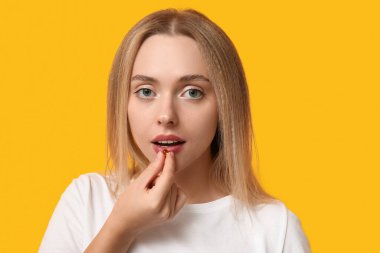 Sarı arka planda vitamin hapı alan genç bir kadın, yakın plan.