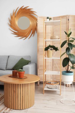 Rafları, çiçekleri, aynası, masası ve kanepesi olan şık bir oturma odası.