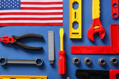 Mavi arka planda Amerikan bayrağı ve oyuncak aletleri. İşçi Bayramı kutlamaları