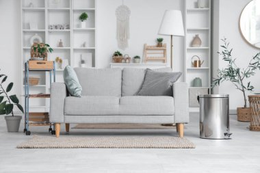 Kanepe, raf üniteleri ve çöp kutusuyla aydınlık oturma odasının içinde.