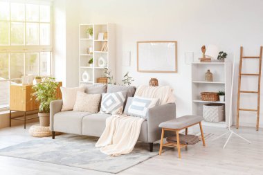 Gri kanepeli, raf üniteli ve çerçeveli aydınlık oturma odasının içi