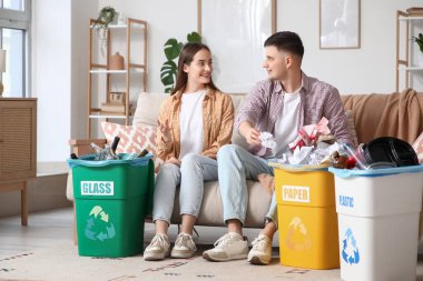 Evdeki çöp bidonlarını düzenleyen genç bir çift. Küresel Geri Dönüşüm Günü