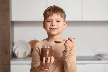 Mutfakta bir kavanoz çikolata ezmesi olan tatlı bir çocuk.