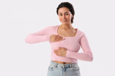 Genç Afro-Amerikalı kadın göğsünü beyaz arka planda kontrol ediyor. Kanser farkındalığı kavramı