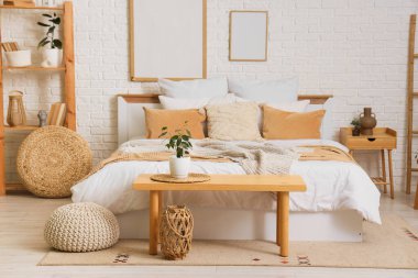 Büyük yataklı, ahşap banklı ve raf üniteli rahat bir yatak odası.