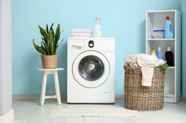 Modern çamaşır makinesi, hasır sepeti ve deterjan şişeleriyle şık bir çamaşır odası.