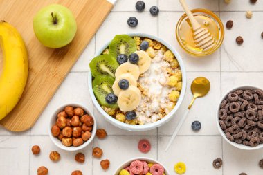 Sağlıklı mısır gevreği kasesi yoğurtlu, taze meyve ve fındıklı beyaz fayanslı