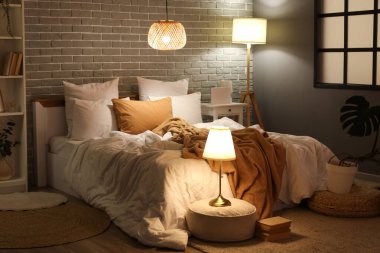 Geceleri rahat yatağı ve parlak lambaları olan modern yatak odasının içinde.