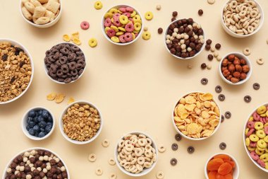 Farklı lezzetli mısır gevrekleri, böğürtlen ve fındıklı bej arkaplanlı kaselerden yapılmış çerçeve.