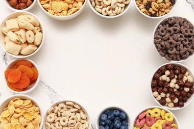 Farklı lezzetli tahıllar, böğürtlenler ve grunge beyaz arka planda kuru meyveler içeren kaselerden yapılmış çerçeveler.