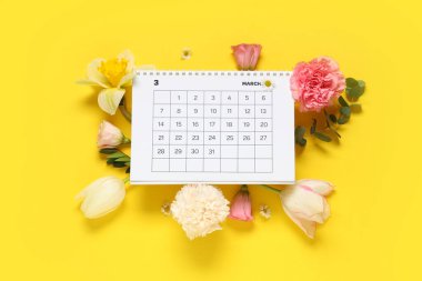 Mart ayının kağıt takvimine ve sarı arkaplanda güzel bahar çiçeklerine sahip kompozisyon