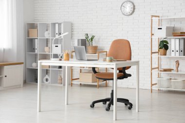 Çalışma yeri ve raf üniteleri olan modern ofisin içi