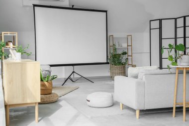 Boş projektör ekran, kanepe ve bitkilerle aydınlatma odasının içi