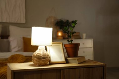 Boş çerçeveli parlayan lamba, kitap ve çiçek akşam yatak odasında klozette.