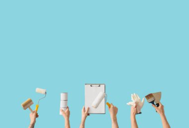 Mavi arka planda boyacı aletleri ve panosu olan erkek eller