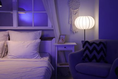 Masası, koltuğu ve parlayan lambası olan karanlık yatak odasının içi.