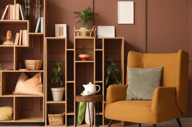 Odanın içinde ahşap raf ünitesi, bitkiler ve koltuk var.