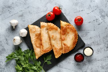 Lezzetli cheburekler, taze sebzeler ve grunge masasında soslar.