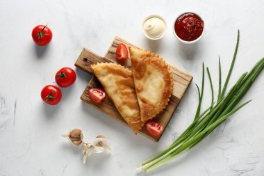 Lezzetli cheburekler, taze sebzeler ve soslar beyaz grunge masasında.