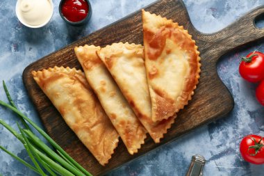 Lezzetli cheburekler, taze sebzeler ve soslar mavi grunge masasında.